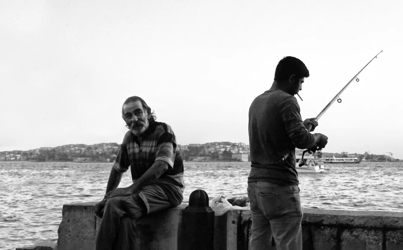 two guys fishing off the waterfront in the rain