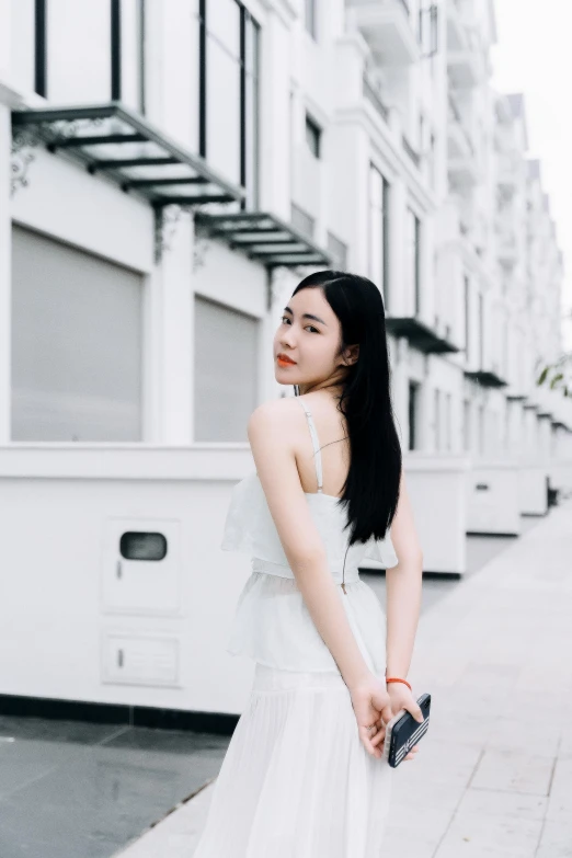 a woman standing on a sidewalk in white