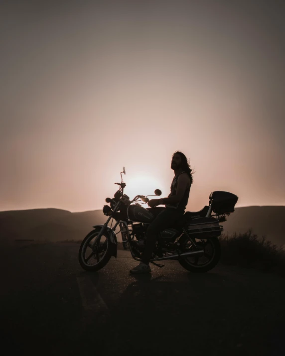 a person sitting on a motorcycle next to the sun