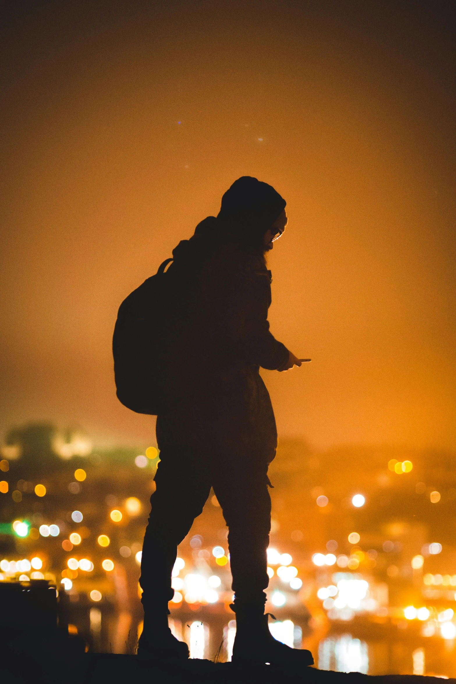 a silhouette of a person on a hill overlooking a city at night