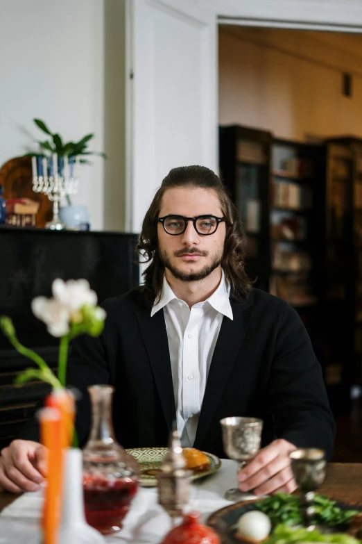 a man sitting at a table in front of a plant