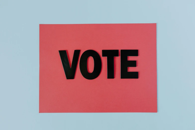 a close up of a red square with the word vote cut out on it