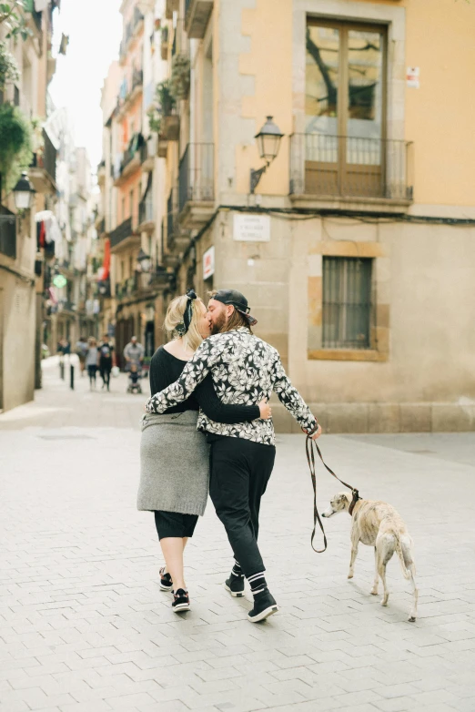 a man and a woman walking two dogs down a city street