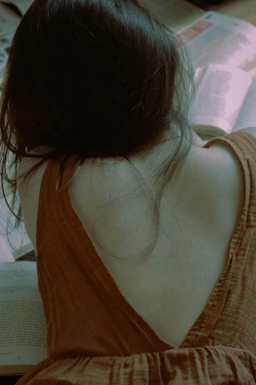 the back of a woman's neck with a book in her lap