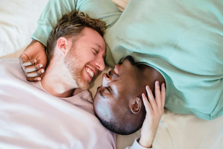 two people laying on a bed sharing a laugh