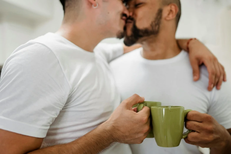 a pair of men hugging each other while holding mugs