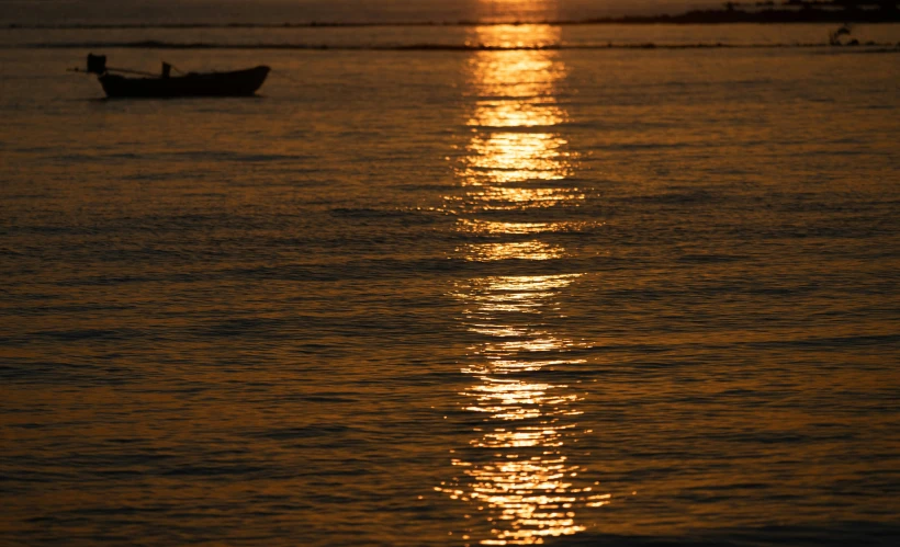 the setting sun and a boat in the ocean