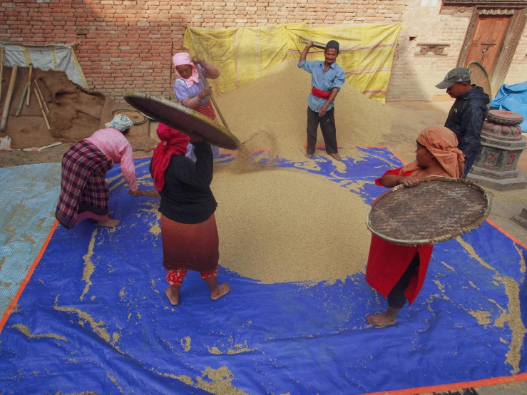 a group of men putting sand into a large drum