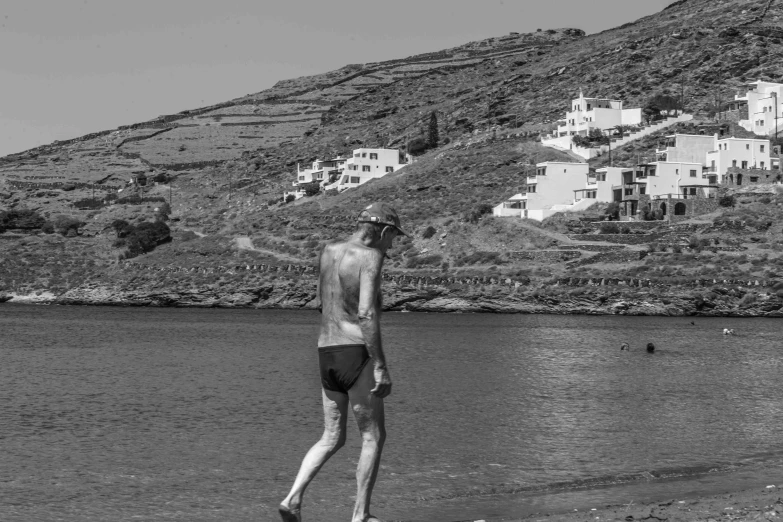 man standing on beach near ocean and houses