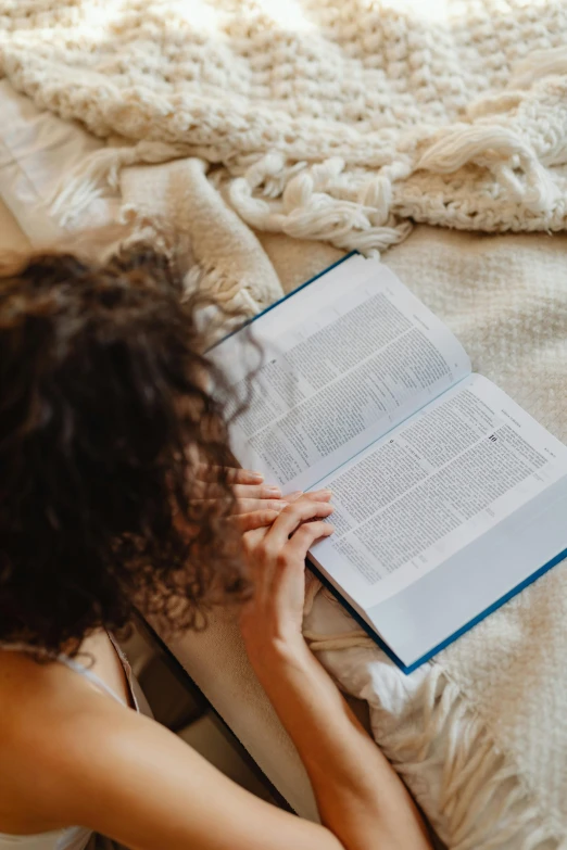 the woman is reading her own book on the bed