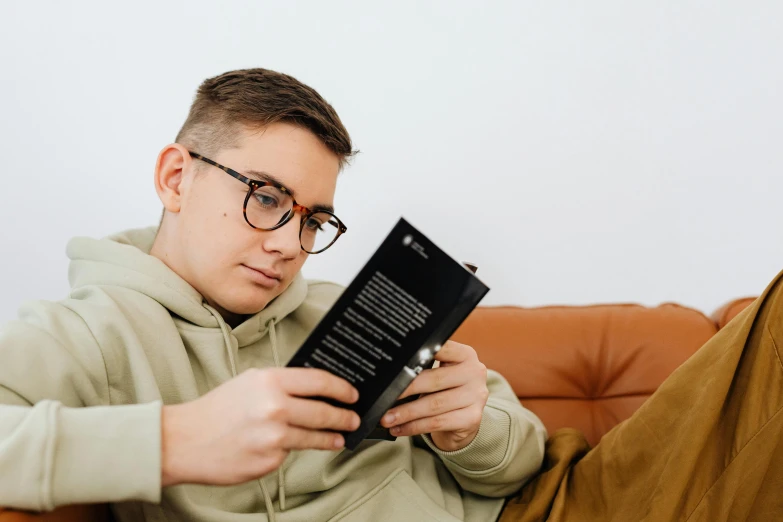 man in a grey sweatshirt holding a black book