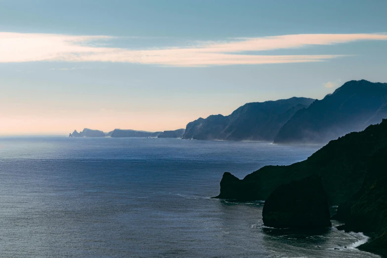 a body of water next to a rocky cliff