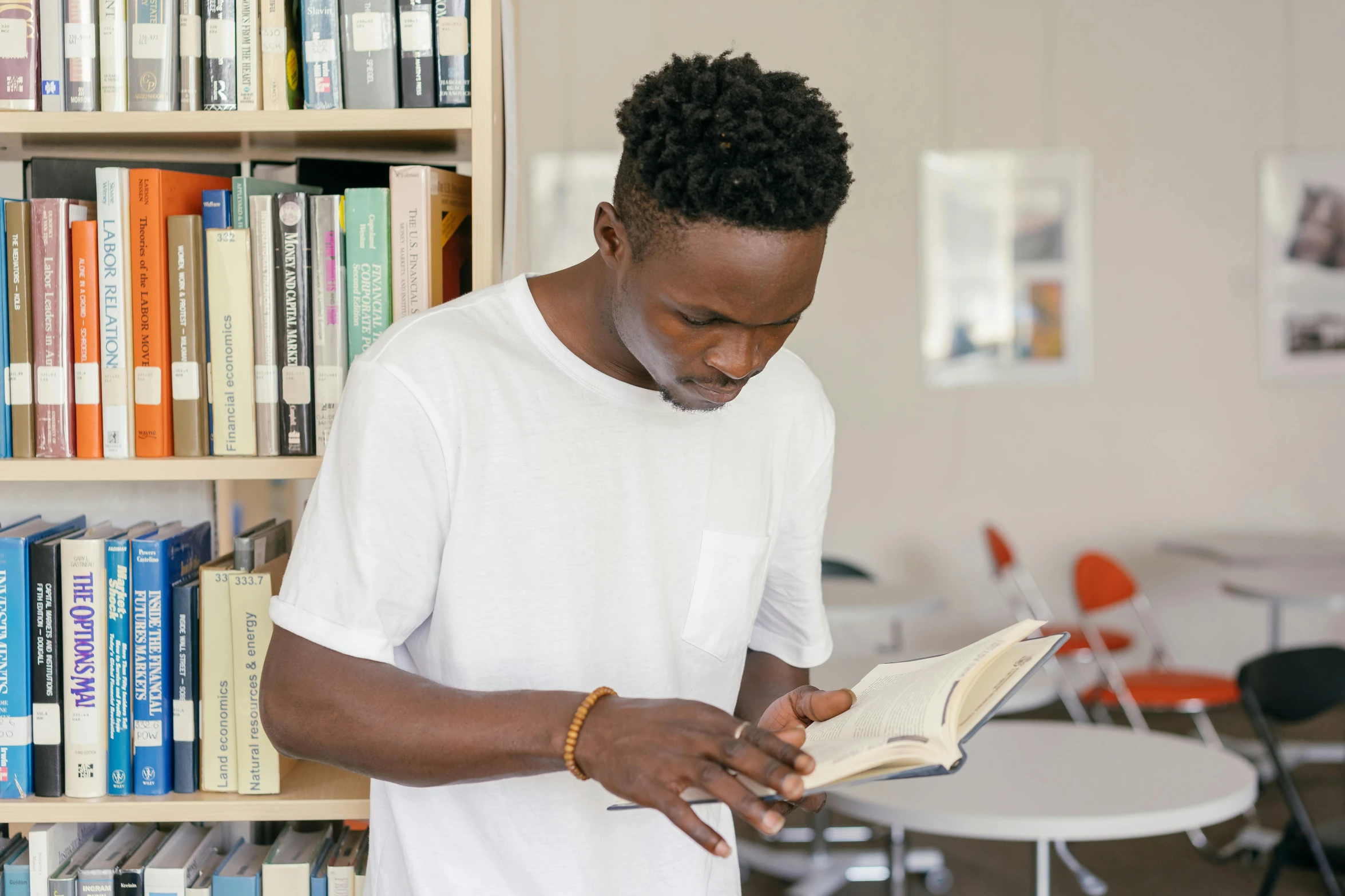 a man reading a book in front of bookshelves