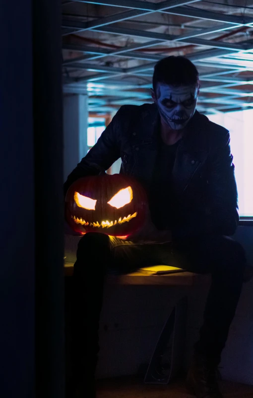 a man sitting on a bench with his hand glowing in the light of a jack o lantern