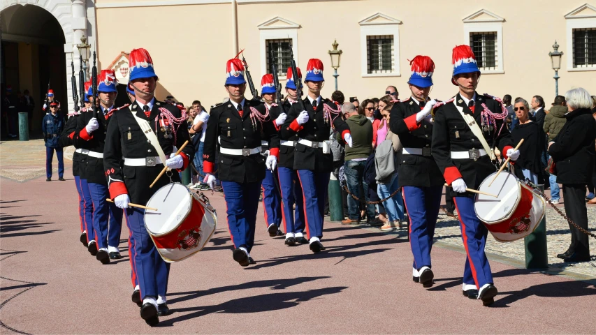 soldiers in uniforms marching down the street, while others watch