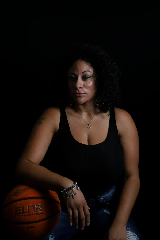a woman in black shirt sitting next to a basketball