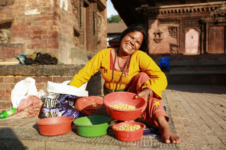 a woman is sitting by her food at a brick sidewalk