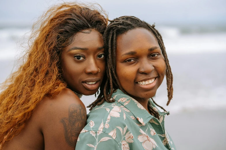 two women are standing together by the ocean