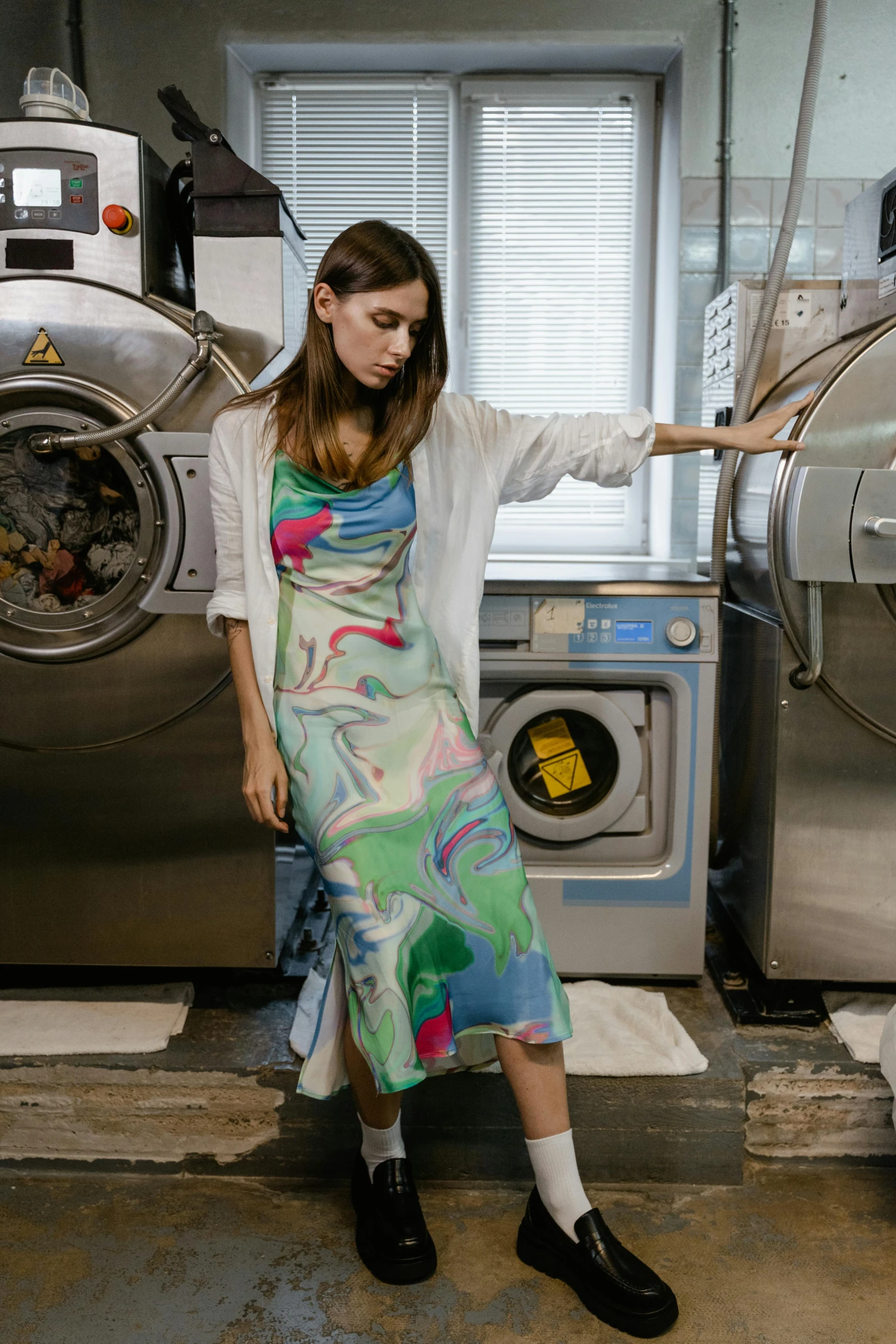 a beautiful woman in a dress standing next to a washer