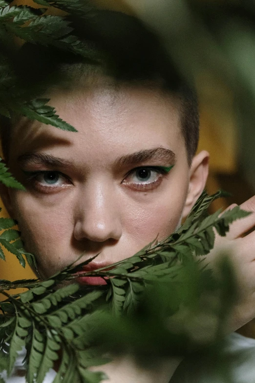 a girl is peering through the leaves on her finger