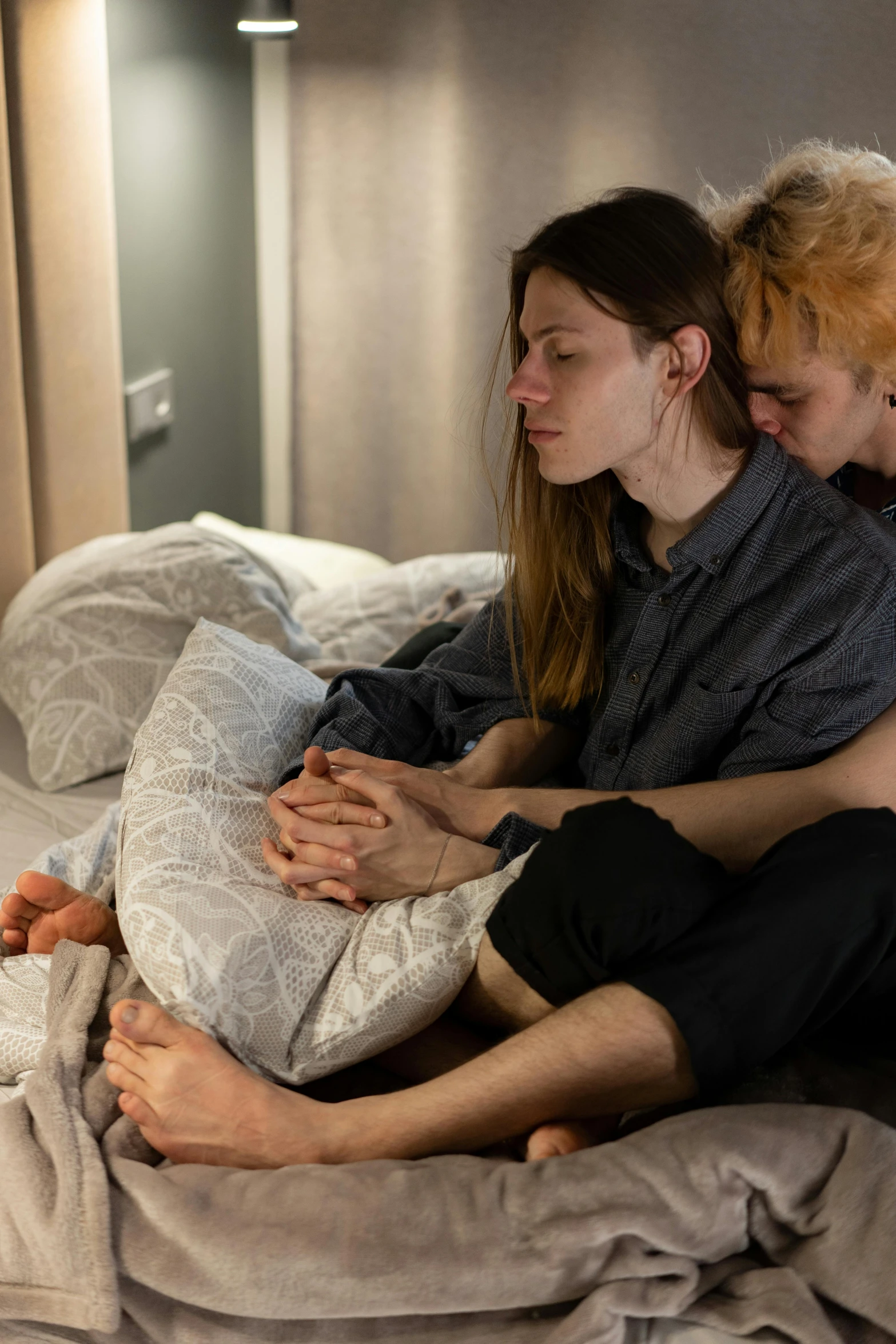 two people that are sitting on a bed