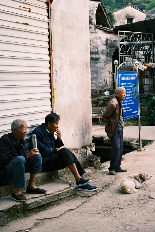 two men sitting on steps in the middle of a village