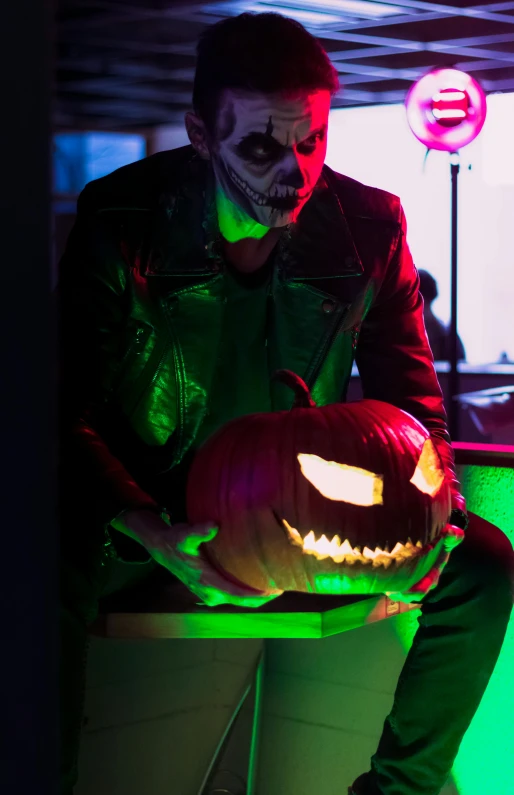 the man is sitting on the counter with his hands in a halloween jack - o - lantern