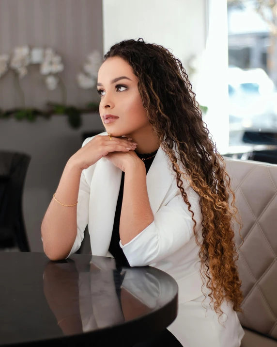 a woman in a black tie and white dress shirt sitting at a table