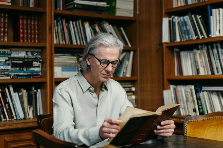 the man is reading an old book at a liry