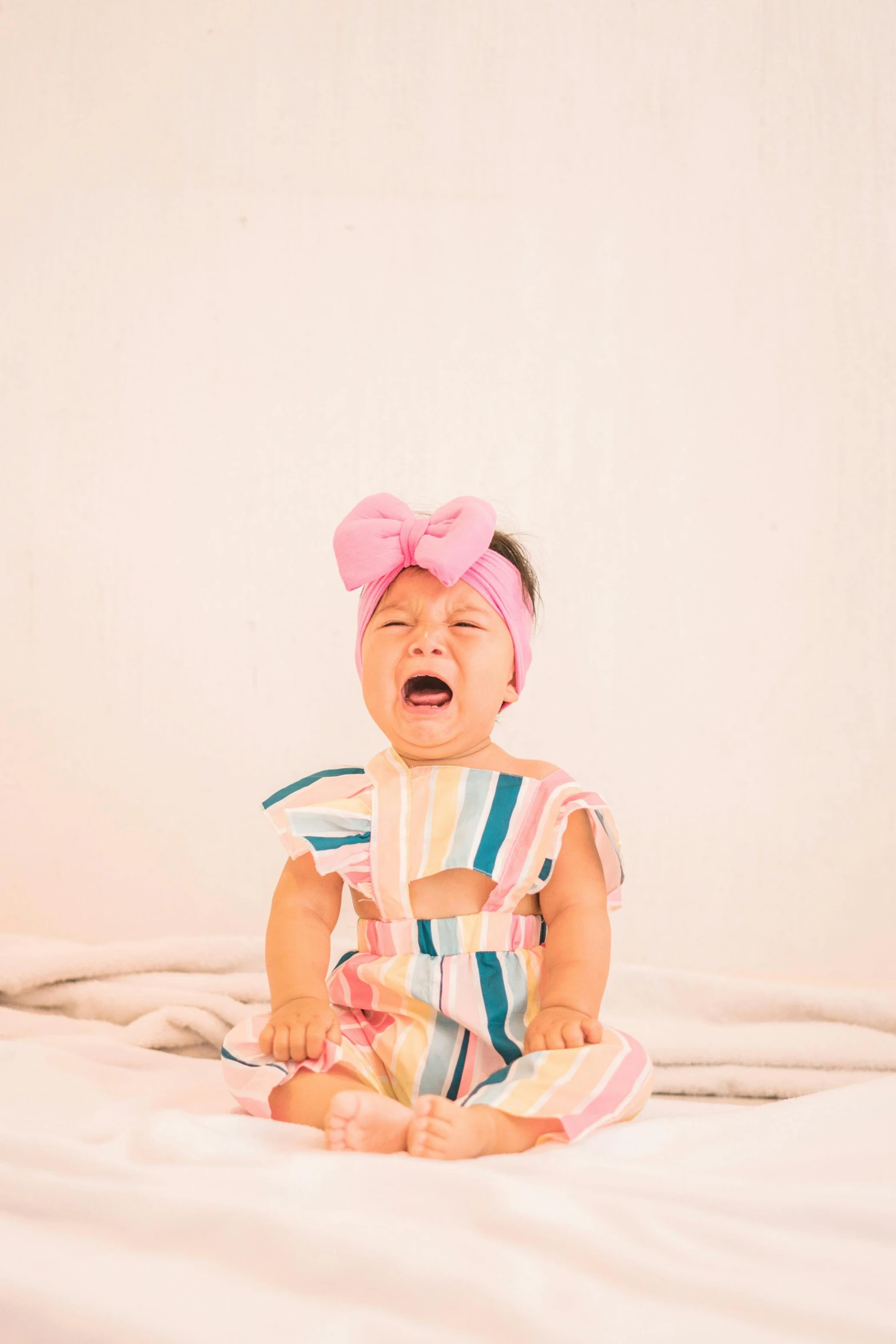 a crying baby sitting on top of a bed