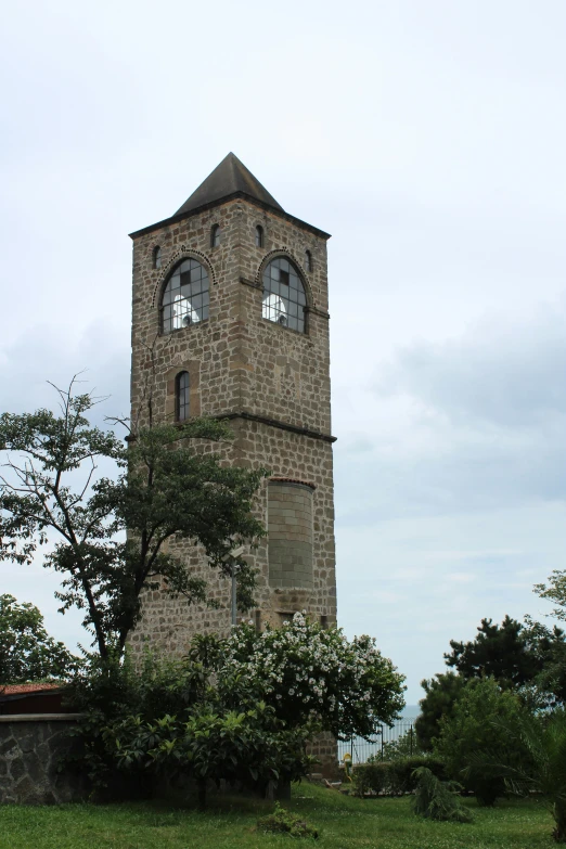 an old tower with three windows with grass in front of it