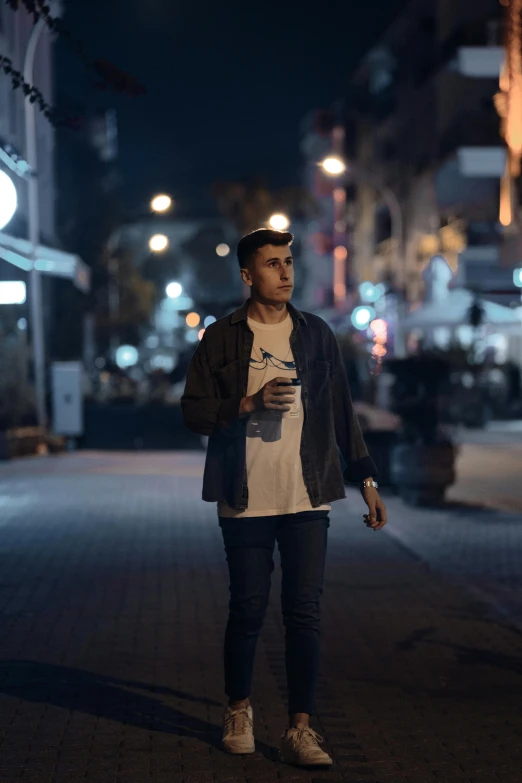 a man standing in the street at night with his cell phone