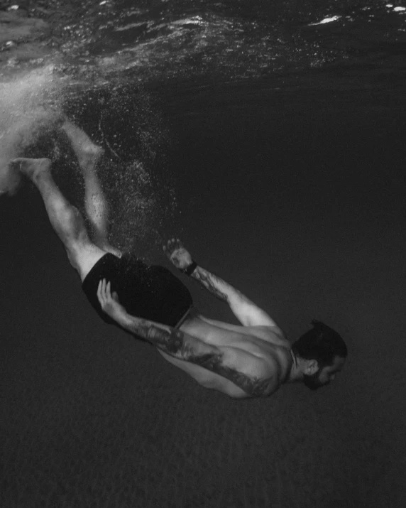 a man is swimming under the water while wearing swim trunks