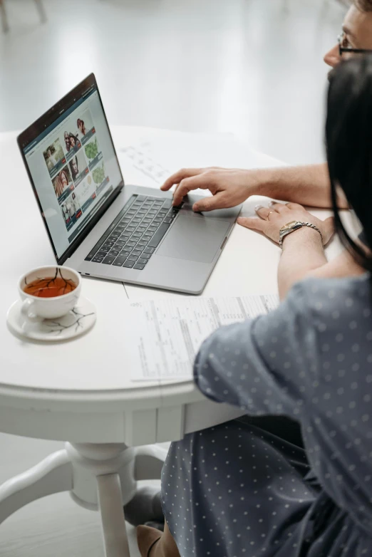 a woman is on her laptop while sitting at the table