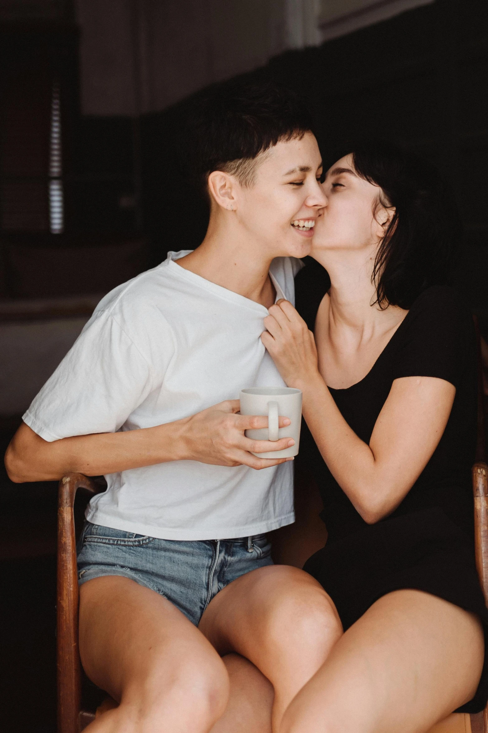 a boy and a girl sitting on a chair kissing
