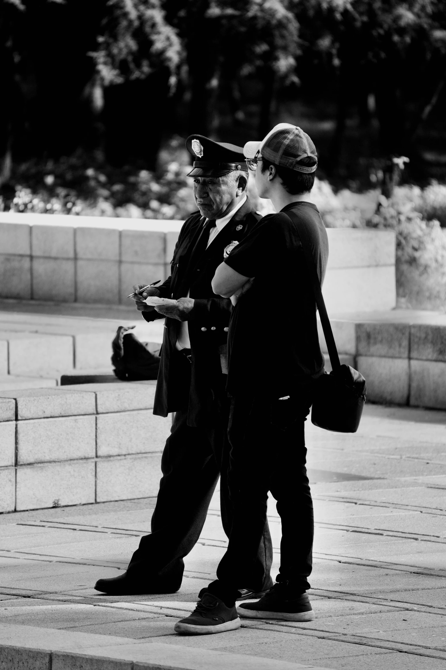 two men are standing on the side walk looking at their phones