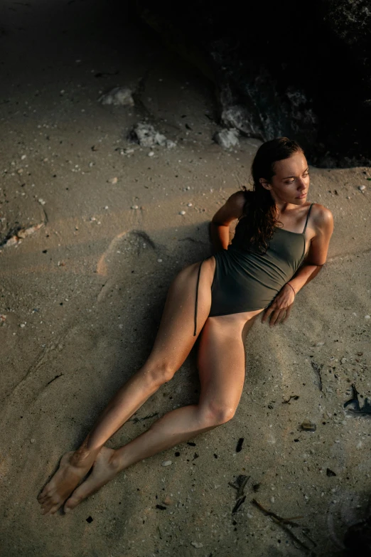 a woman laying on the ground in a dark bathing suit