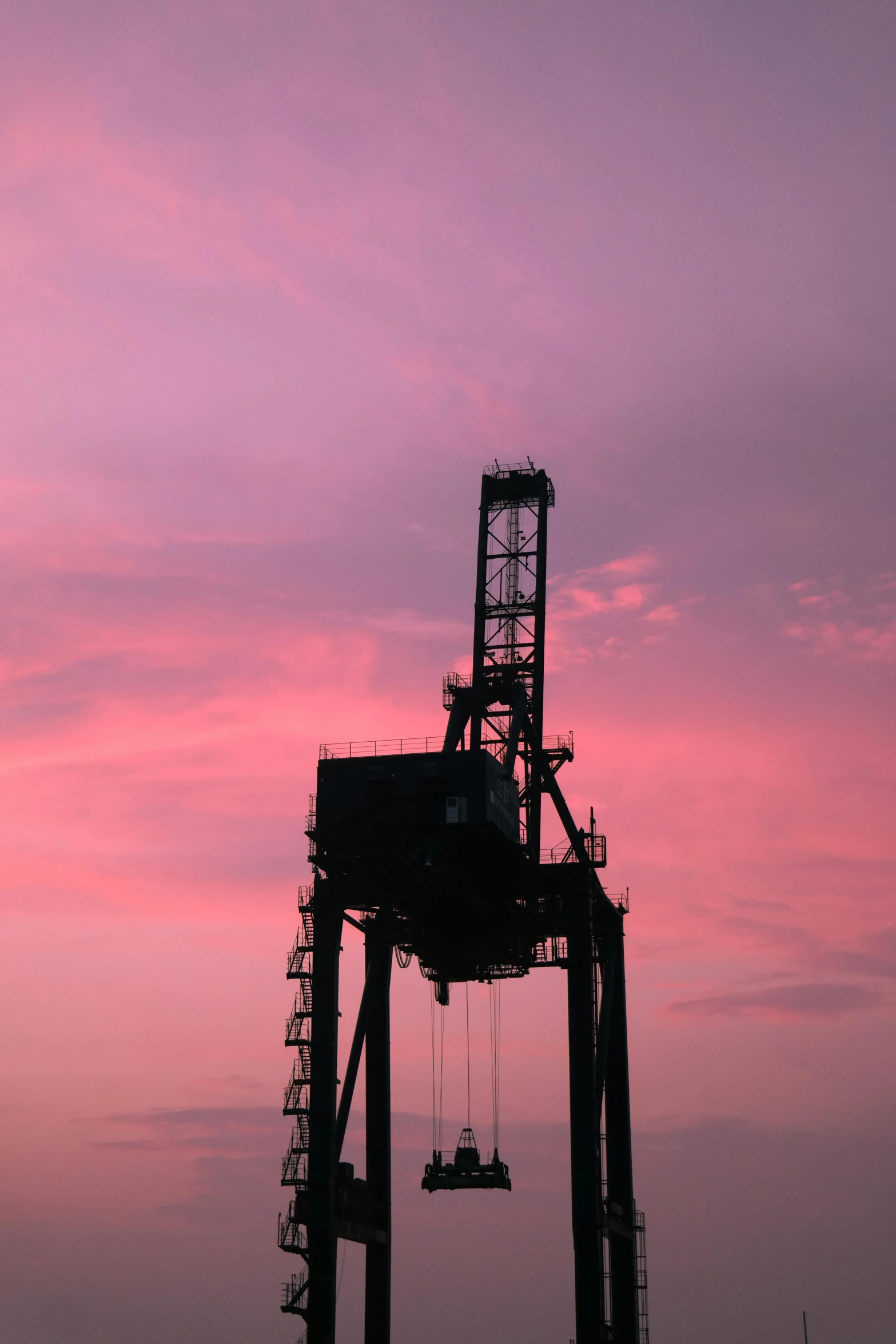 a crane lifts a ship into the water at sunset