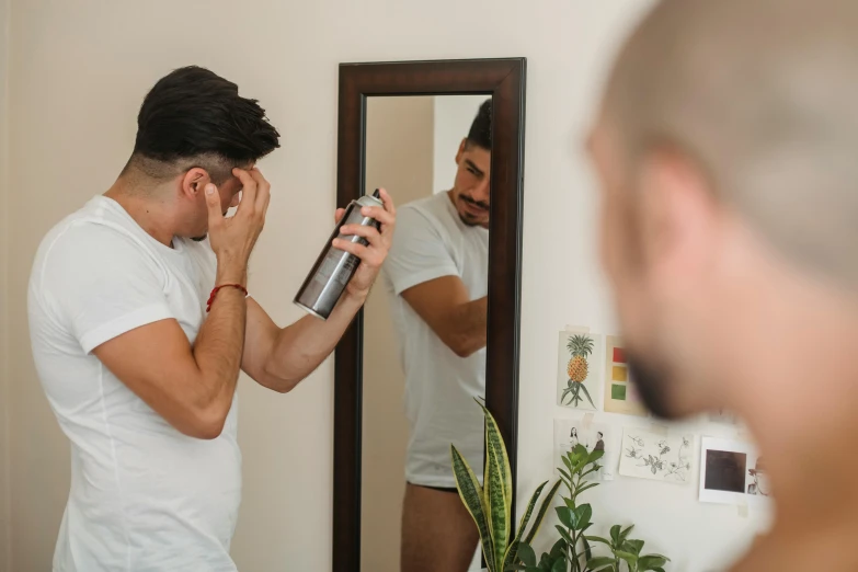 a man uses a hair dryer to dries his hair in front of a mirror