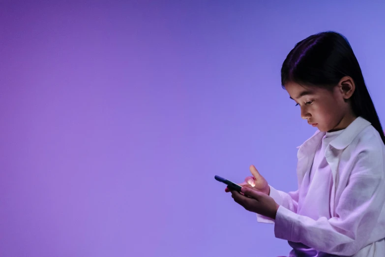 a girl using a smart phone on a pink background