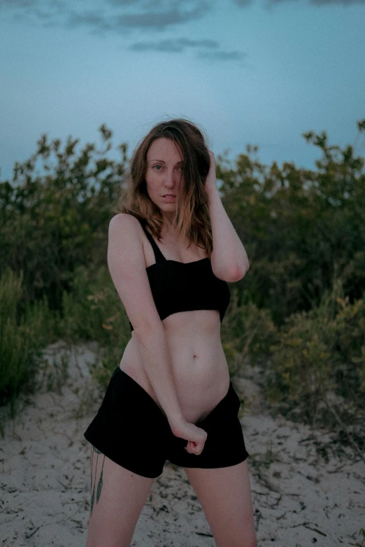 the woman is posing with her panties in a tight black swimsuit