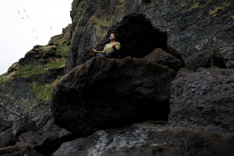 a man sitting on top of a rock formation near a cliff