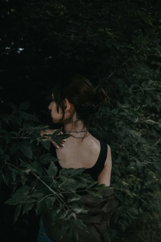 woman looking around a dense foliage covered tree