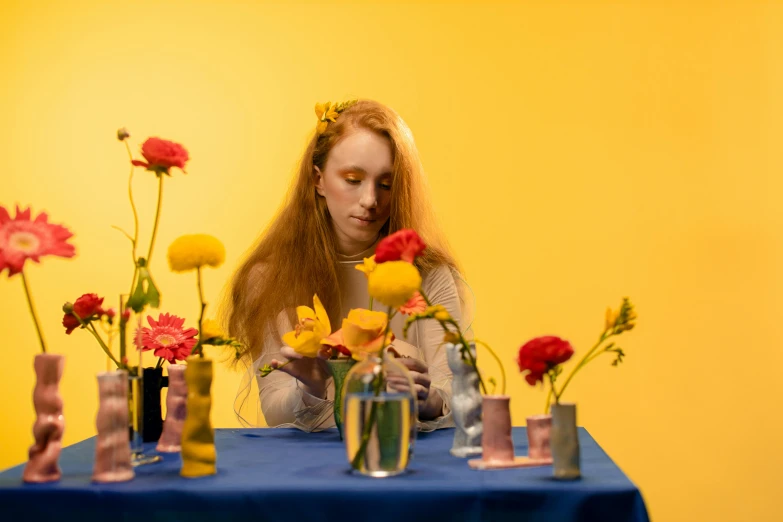 a beautiful young woman sitting at a table surrounded by flowers