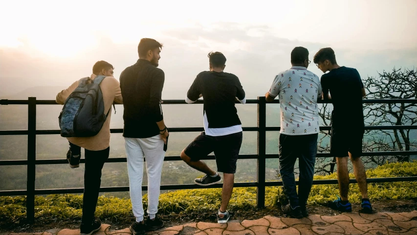 a group of people stand on the edge of a fence