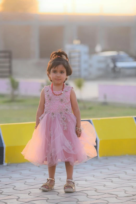 a small child wearing a pink dress on the sidewalk