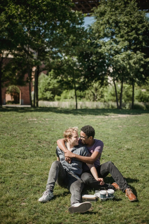 two people are sitting in the grass on a skateboard