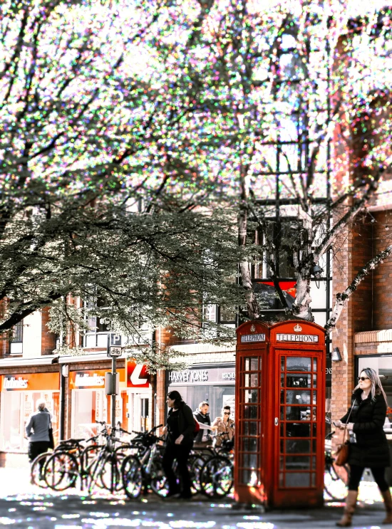 people walking past a red telephone box and parked bikes