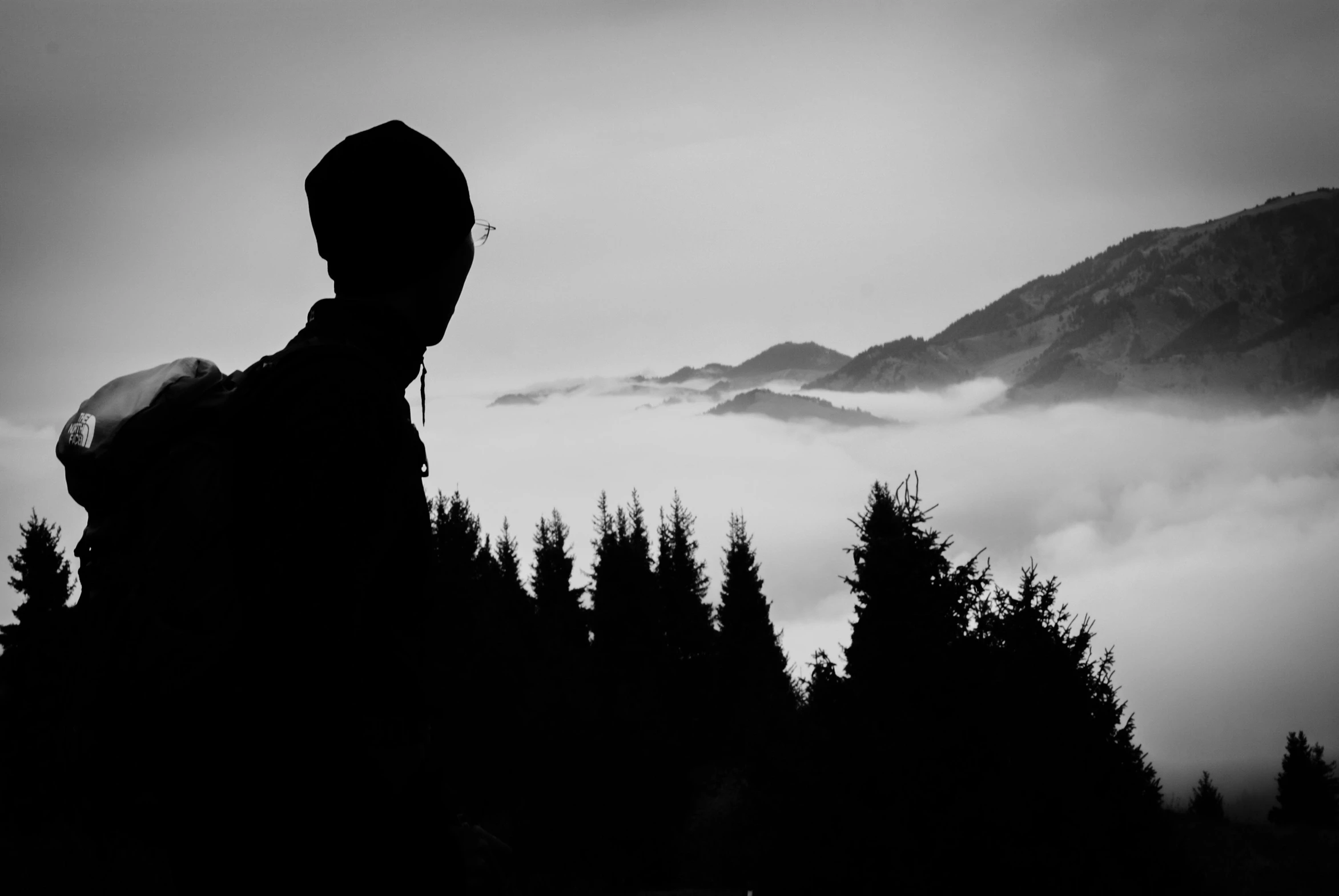 a person with headphones on standing in front of trees and clouds