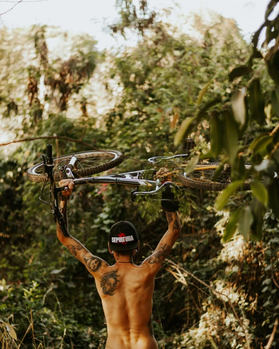 an individual stands by a tree with his bicycle